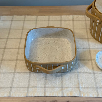 Elevated front view of the square dish with a tan handle facing forward.