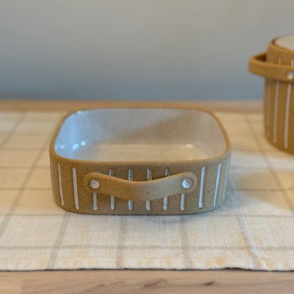 Side view of the small square dish's white-striped exterior and attached handle.