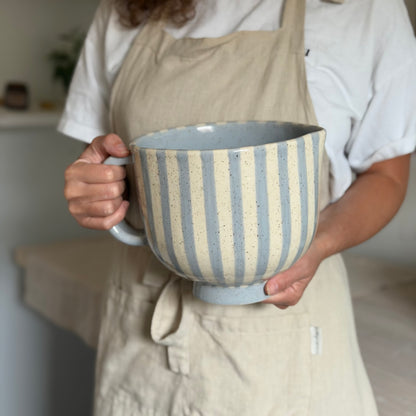 Person holding the striped ceramic mixing bowl level to show its size.