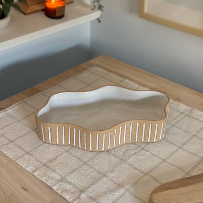 Wavy striped stoneware dish on checked linen, viewed from above at an angle.