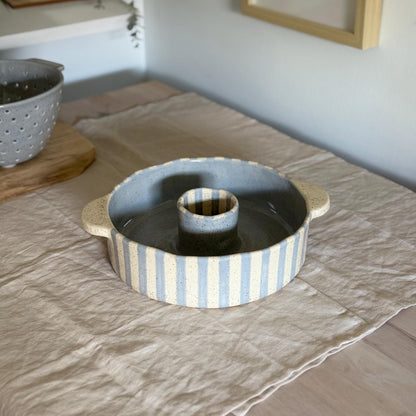 Blue and cream striped ceramic bundt pan with a center tube and two side handles.