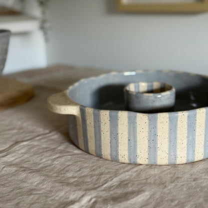Side detail of the bundt pan's striped wall, cream handle and central tube.