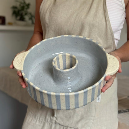 Person holding the ceramic bundt pan level, showing its blue-gray glazed interior.