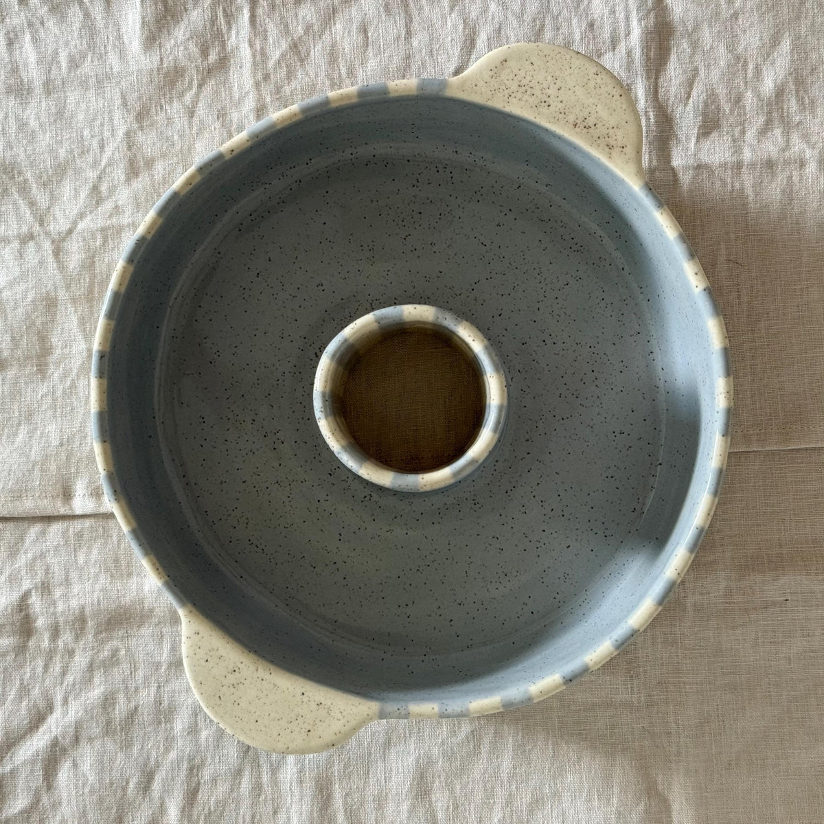 Overhead view of the round blue-striped bundt pan and two cream handles.