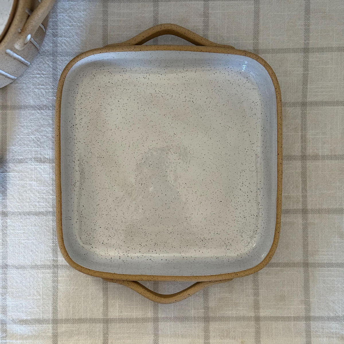 Overhead view of the square baking dish's glazed interior and two tan handles.
