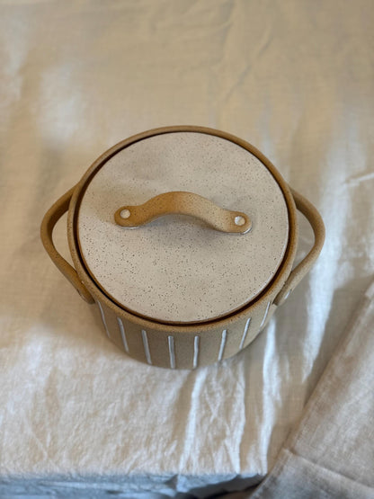 Overhead view of the Striora pot with its white glazed lid and curved tan handle.