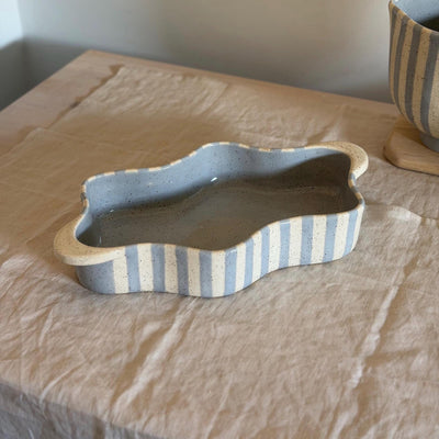 Blue and cream striped ceramic baking dish with wavy sides and broad end handles.