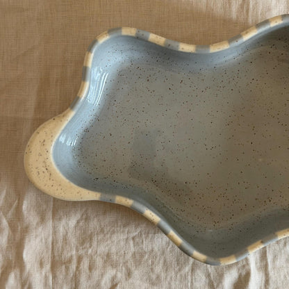 Detail of the wavy dish's speckled blue-gray interior and cream handle.