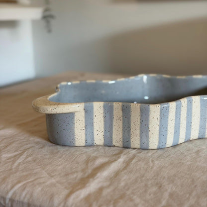 Side view of the blue-striped dish showing its undulating wall.