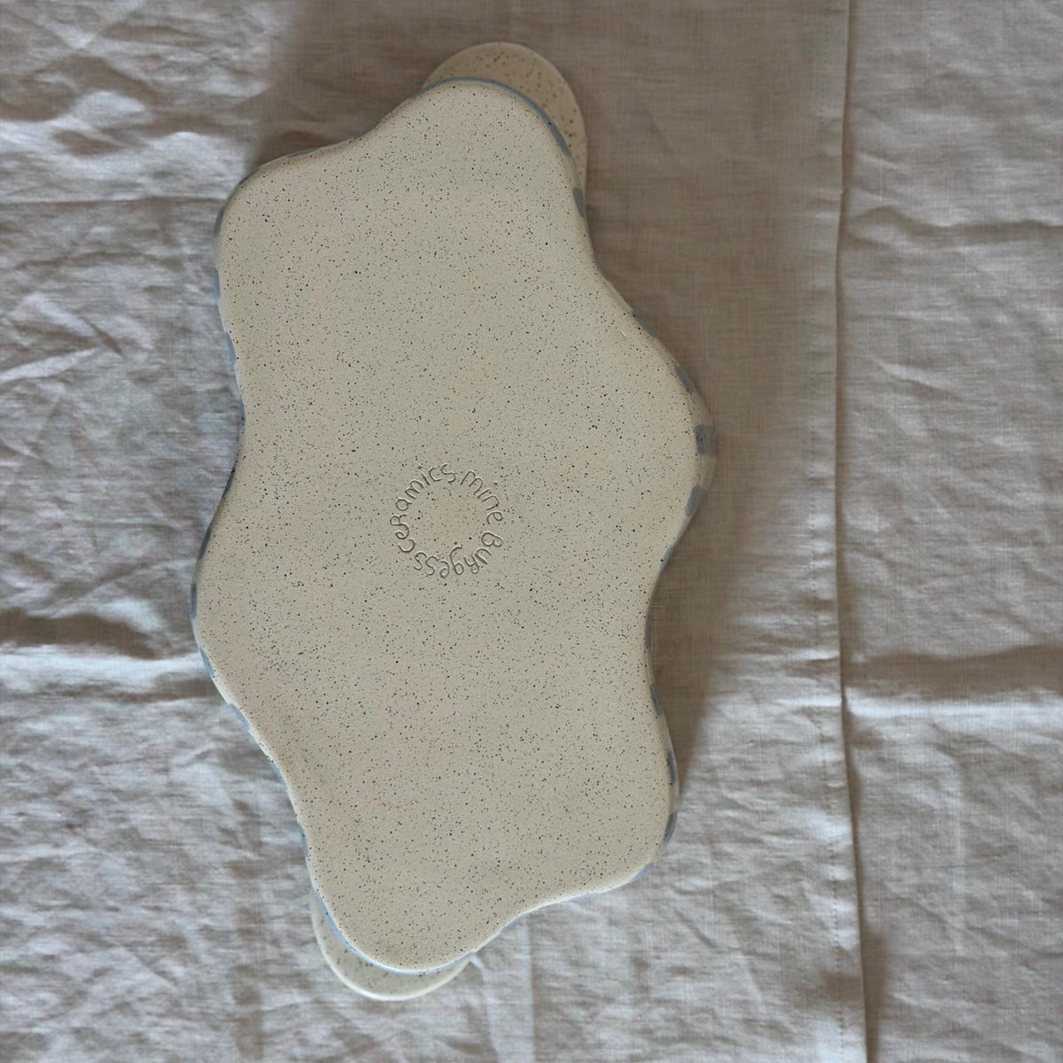 Underside of the wavy striped dish with a circular maker's stamp.