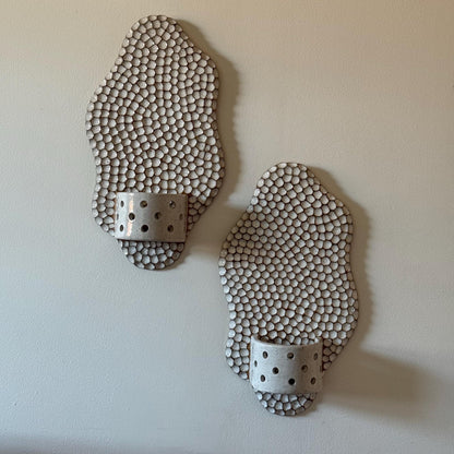 Two unlit honeycomb Wavora candle holders mounted on a pale wall.