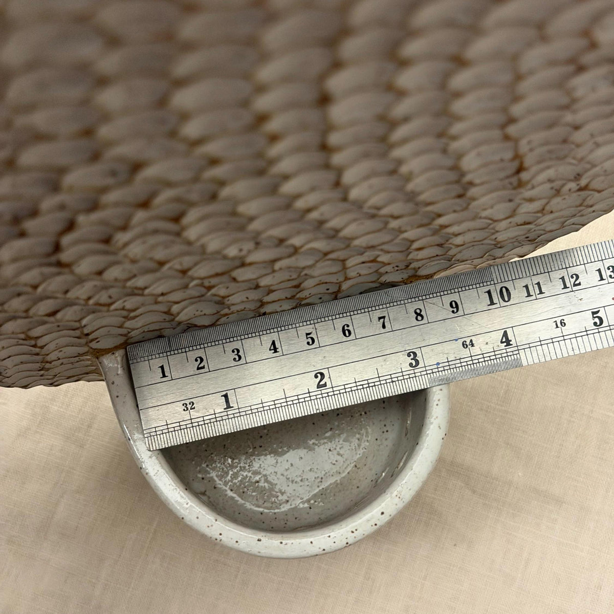 Ruler across the candle cup beneath the wavy honeycomb backplate.