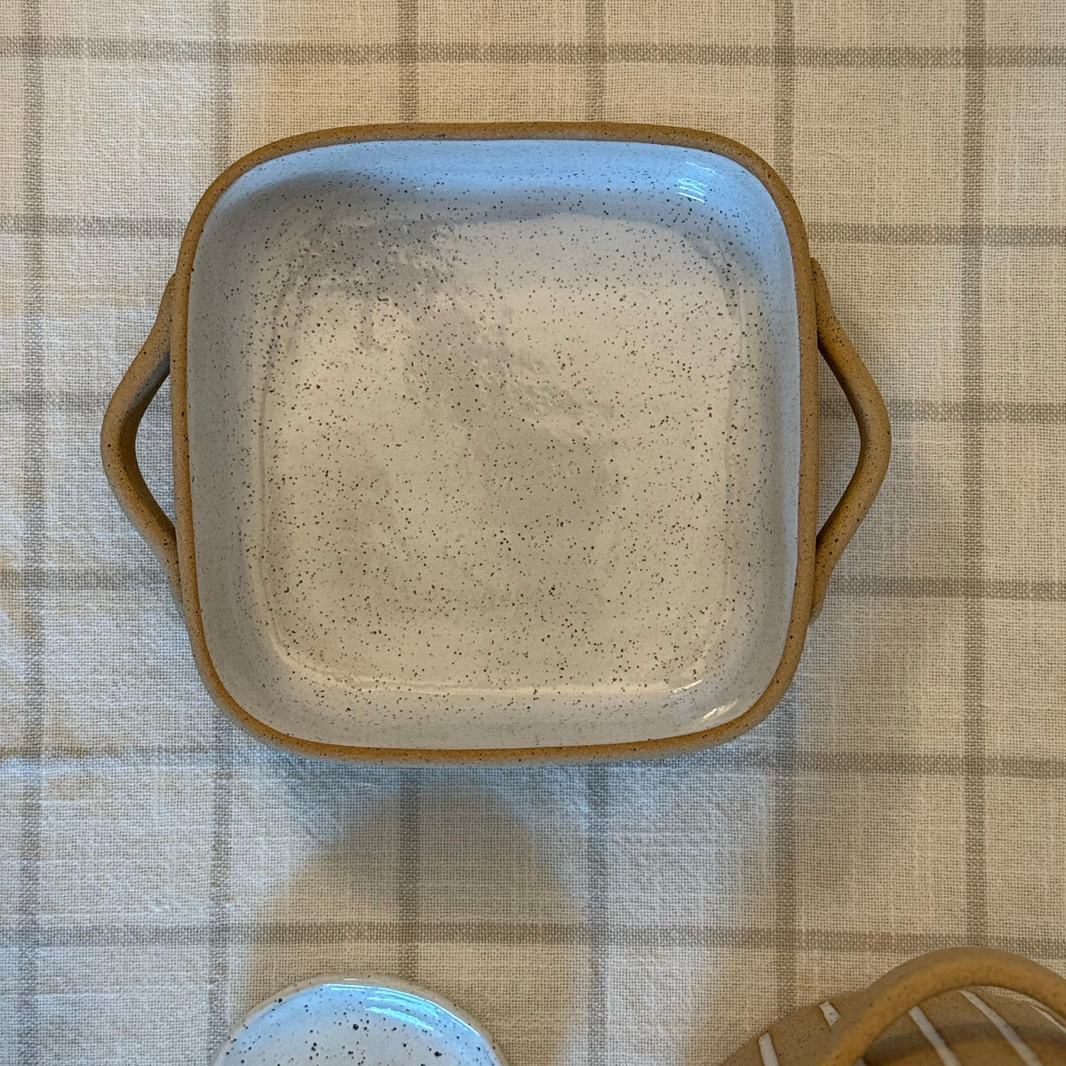 Closer overhead view of the square Striora dish's speckled glazed interior.