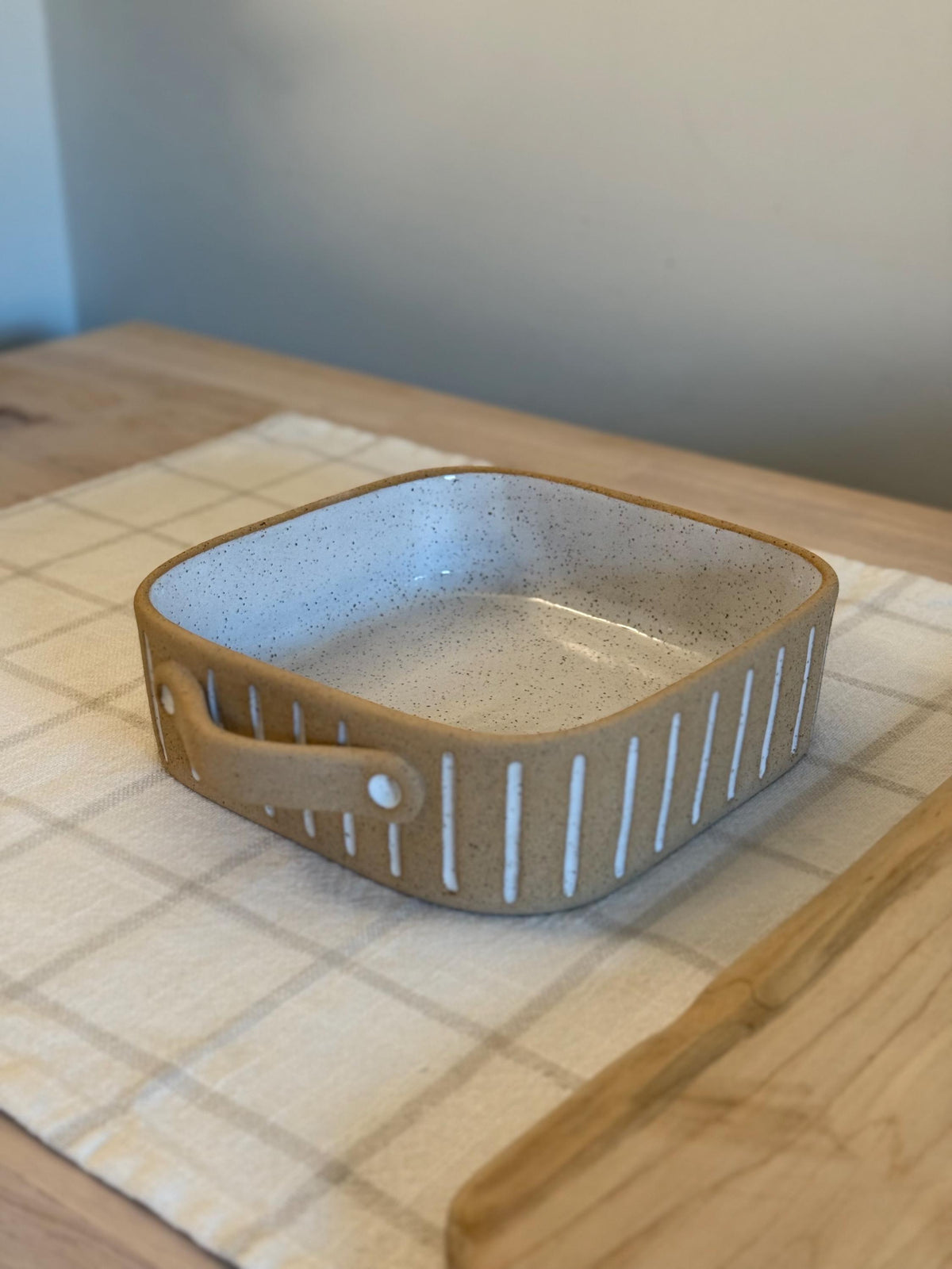 Angled view of the small square Striora dish on a wooden table.